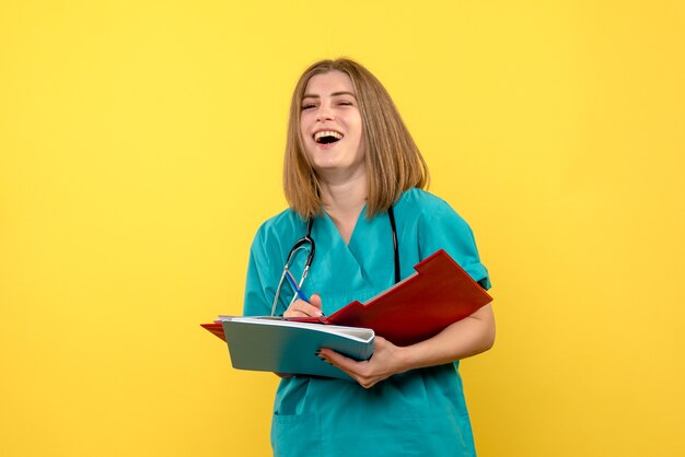 Ärztin der Vorderansicht mit Dokumenten auf medizinischem Notfall des gelben Bodenkrankenhauses