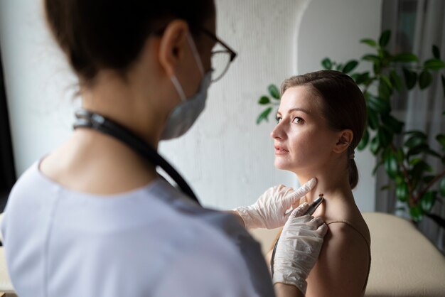 Ärztin diagnostiziert ein Melanom am Körper einer Patientin