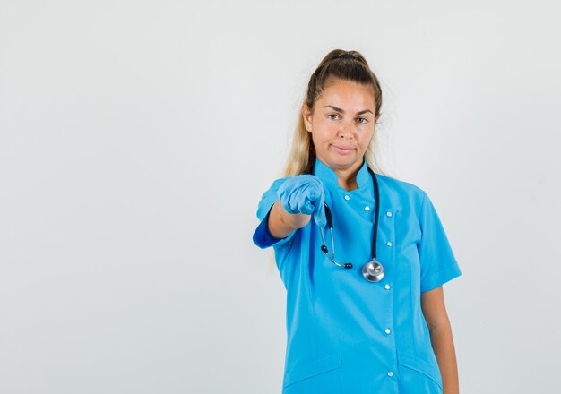 Ärztin, die Finger auf Kamera in blauer Uniform zeigt