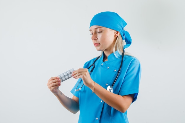 Ärztin, die Packung der Pillen in der blauen Uniform hält