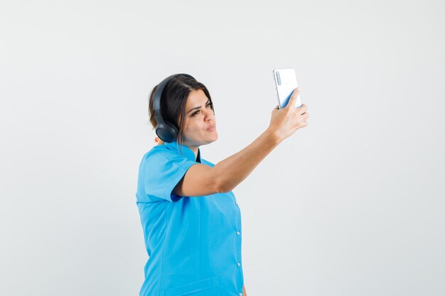 Ärztin, die Selfie macht, während sie Musik in blauer Uniform genießt