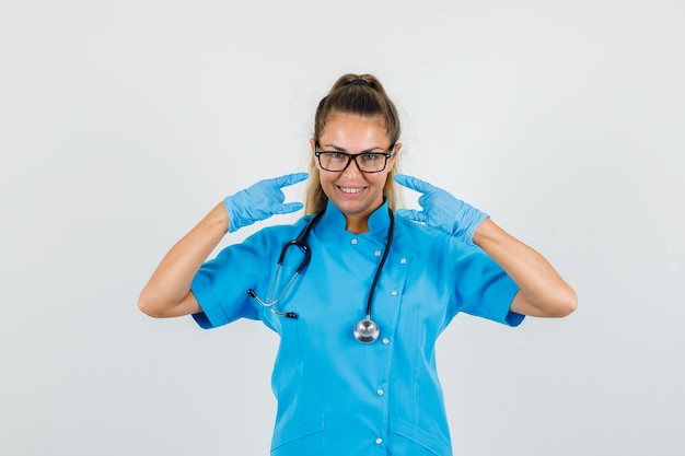 Ärztin, die Steinsymbol mit Händen in der blauen Uniform tut