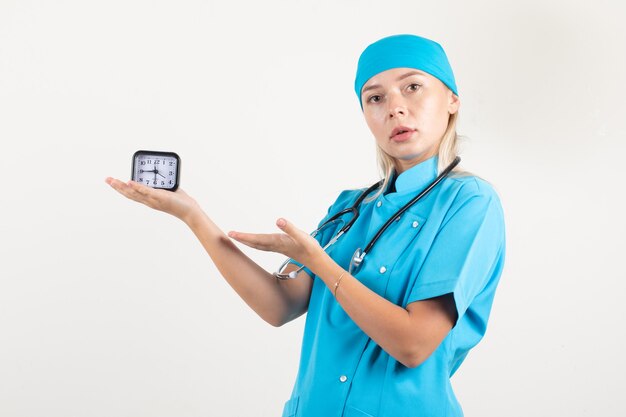 Ärztin in blauer Uniform, die auf Uhr zeigt und vorsichtig schaut