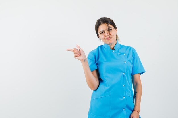 Ärztin in blauer Uniform, die zur Seite zeigt und selbstbewusst aussieht