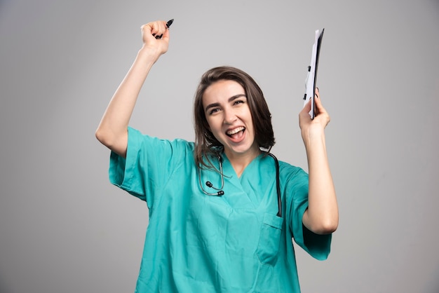 Ärztin in Uniform lachend beim Halten der Zwischenablage. Hochwertiges Foto