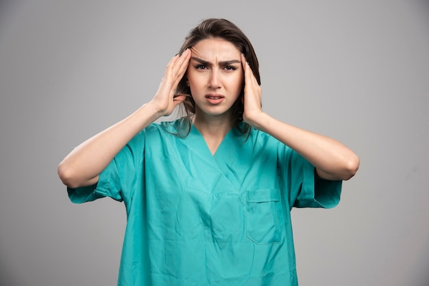 Ärztin mit Kopfschmerzen auf grauem Hintergrund. Hochwertiges Foto