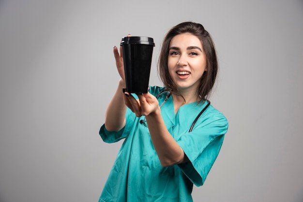 Ärztin mit Stethoskop, das Kaffee hält. Hochwertiges Foto