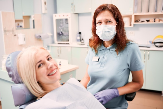 Ärztin sitzt neben dem Patienten in der Zahnarztpraxis