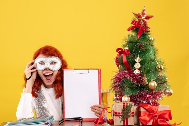 Ärztin trägt Maske um Weihnachtsbaum und präsentiert auf gelb