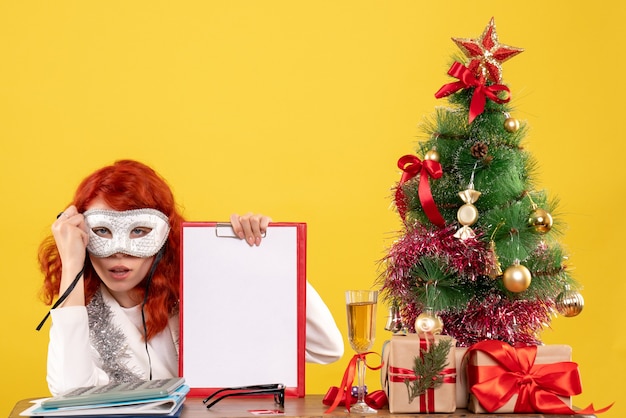 Ärztin trägt Maske um Weihnachtsbaum und präsentiert auf gelb