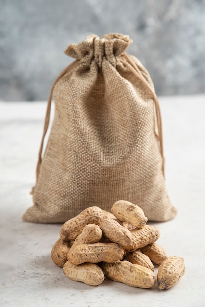 Sackleinen mit gerösteten Bio-Erdnüssen auf Marmortisch.