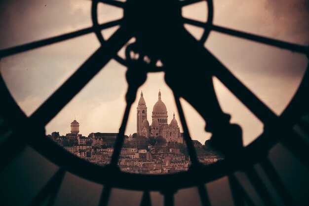 Sacre-Coeur betrachtet durch riesigen Uhrenturm in Paris, Frankreich.