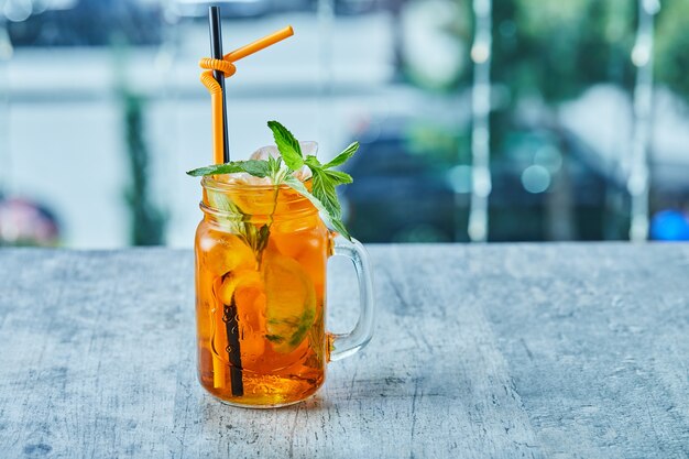 Saftige Limonade mit Stroh und Minze auf der Marmoroberfläche