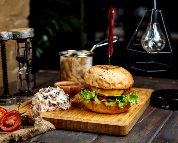 Saftiger Cheeseburger mit Salat auf einem Holzbrett