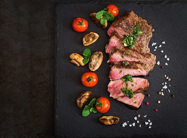 Saftiges Steak mittleres seltenes Rindfleisch mit Gewürzen und gegrilltem Gemüse.