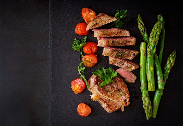 Saftiges Steak mittleres seltenes Rindfleisch mit Gewürzen und Tomaten, Spargel.