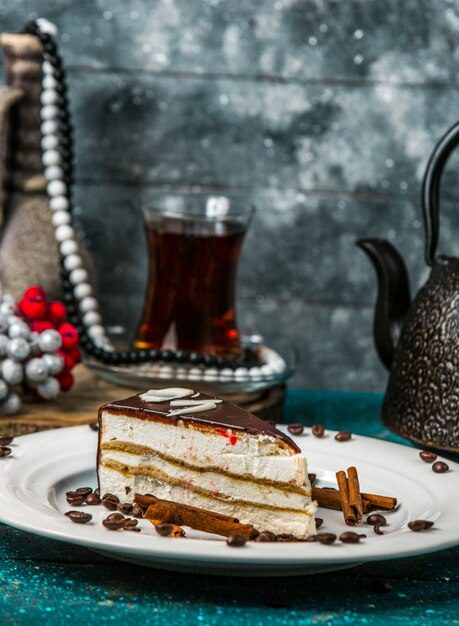 Sahne-Sandwich-Torte mit Chocholate überzogen, dekoriert mit Zimtstangen und Kaffee