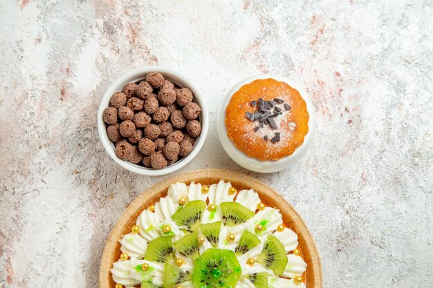 Sahnedessert von oben mit weißer Sahne und geschnittenen Kiwis auf weißem Raum