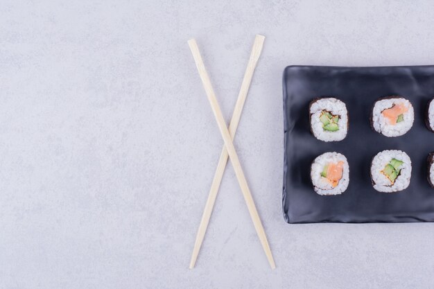 Sake Maki Rolls mit Lachs und Avocado in einer schwarzen Keramikplatte.