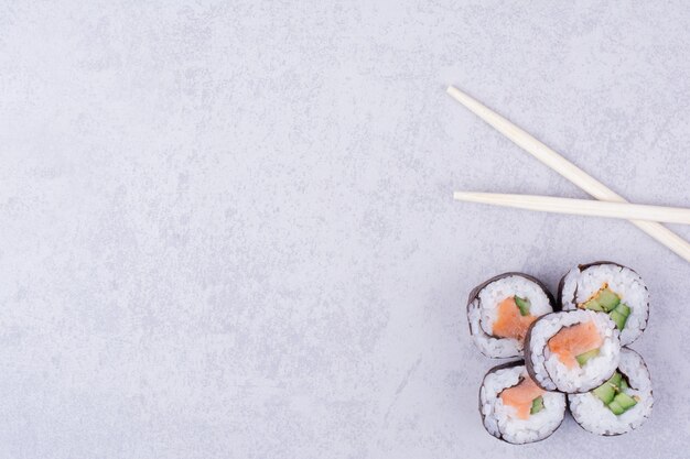 Sake Maki rollt auf grauem Hintergrund mit Stäbchen