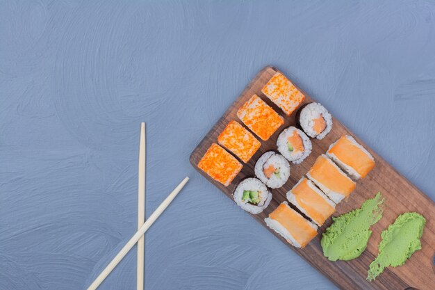 Sake Maki und Philadelphia Brötchen mit Wasabi-Sauce auf einer Holzplatte