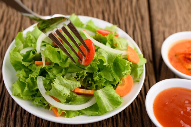Salat auf dem Teller mit Tomate auf Spießgabel.