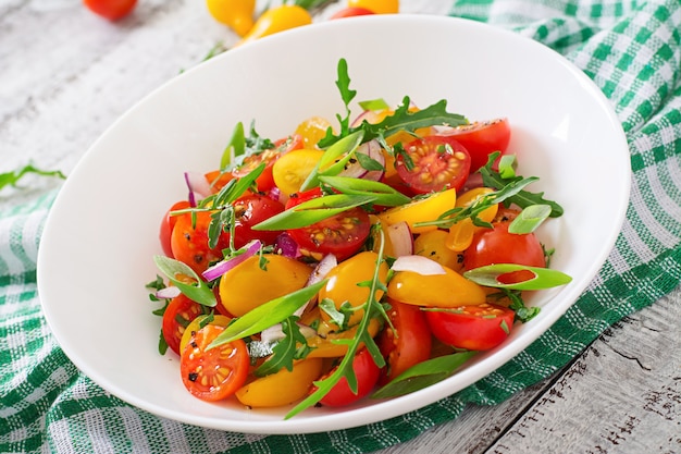 Salat aus frischen Kirschtomaten mit Zwiebeln und Rucola