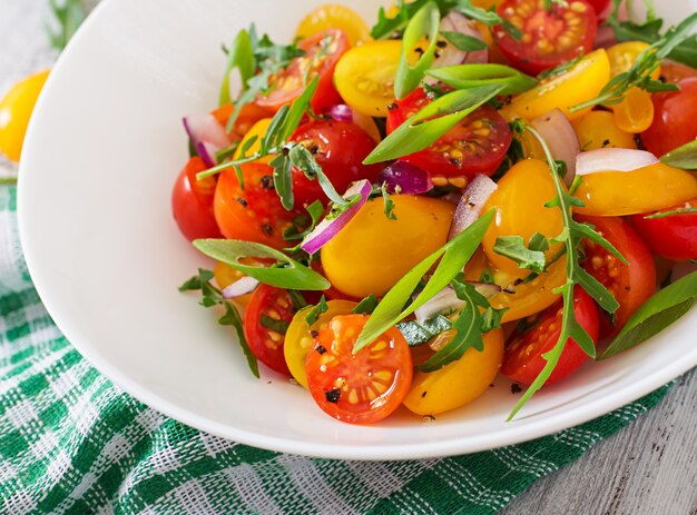 Salat aus frischen Kirschtomaten mit Zwiebeln und Rucola