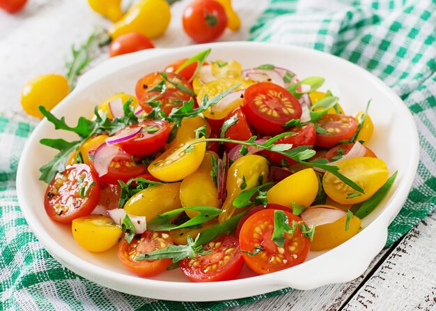 Salat aus frischen Kirschtomaten mit Zwiebeln und Rucola