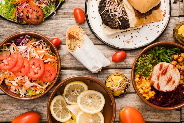 Salat; Limettenscheiben mit Hamburger; Burritoschüssel und Wrap auf dem Tisch
