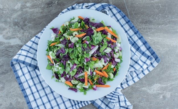 Salat mit frischem Gemüse zubereitet, auf Teller, auf dem Handtuch, auf dem Marmortisch.