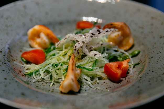 Salat mit Garnele, Tomaten und Reisnudeln, Zucchini auf weißer Platte.