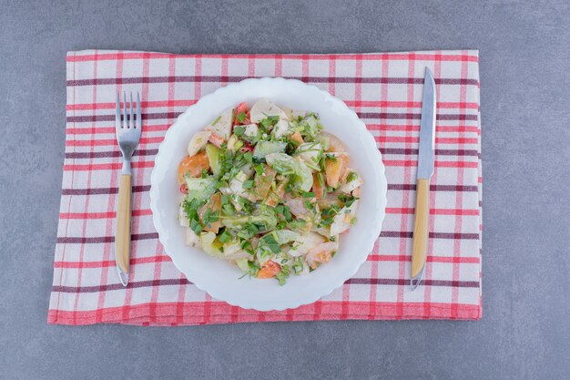 Salat mit gehackten Kräutern und Gemüse auf Betonoberfläche