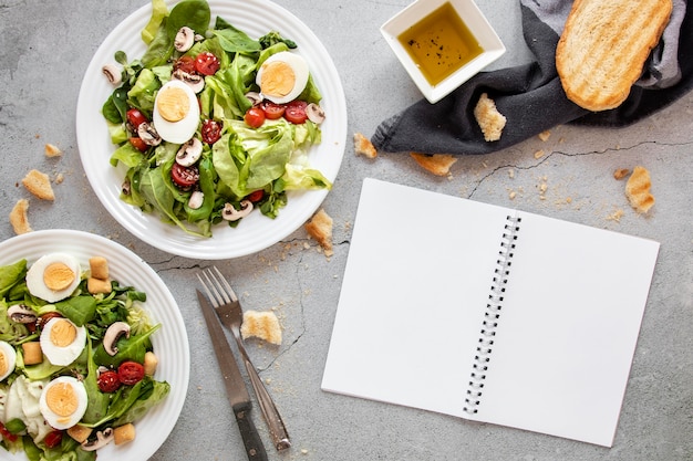 Salat mit Gemüse und Eiern neben Notizbuch