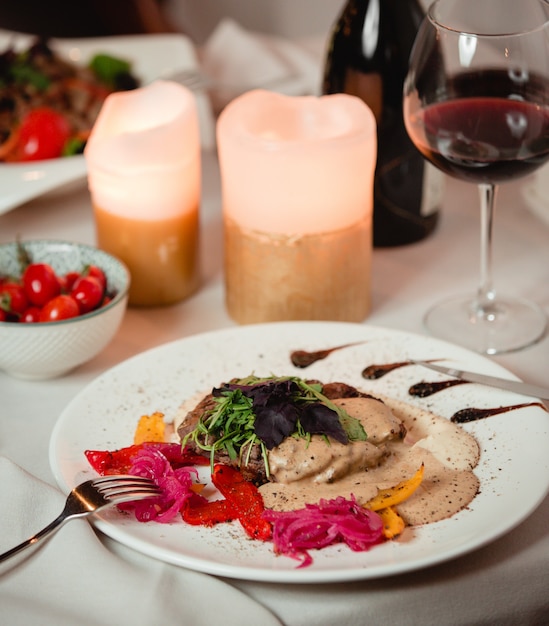 Salat mit kräutern und cremigem dressing mit einem glas rotwein.