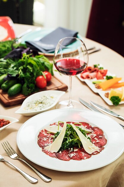 Salat mit Peperoni Kräutern und geschnittenem Parmesan mit einem Glas Rotwein.