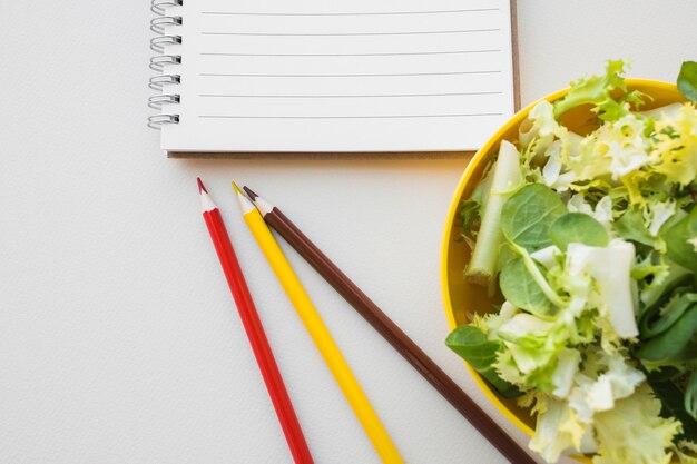 Salat und Bleistifte nähern sich Notizbuch