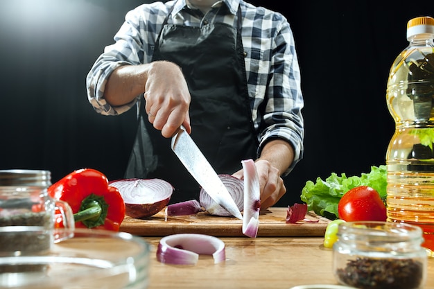 Salat zubereiten. Köchin, die frisches Gemüse schneidet. Kochvorgang. Selektiver Fokus