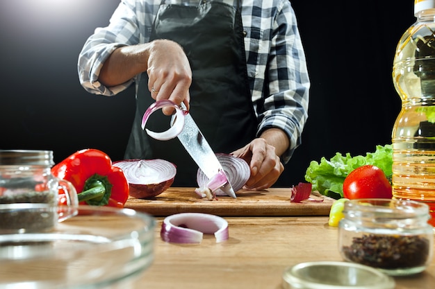 Salat zubereiten. Köchin, die frisches Gemüse schneidet. Kochvorgang. Selektiver Fokus