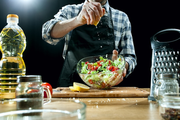 Salat zubereiten. Köchin, die frisches Gemüse schneidet. Kochvorgang. Selektiver Fokus