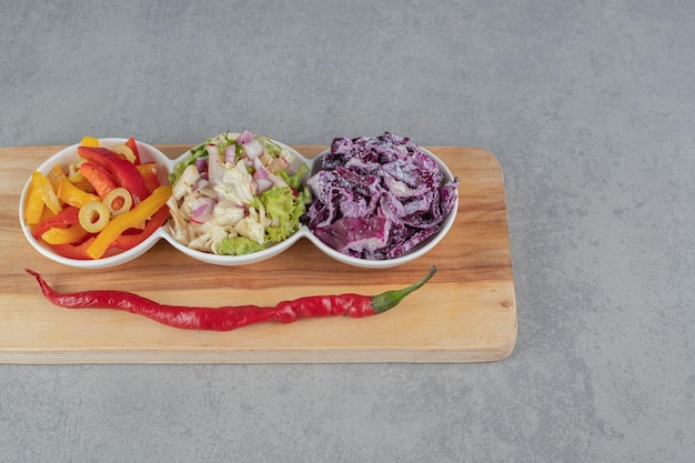 Salatsorten in Tassen auf einer Holzplatte.