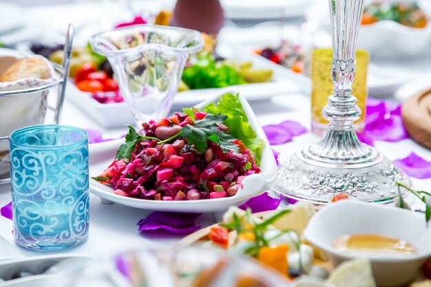 Salatvinaigrette mit Seitenansicht auf einem servierten Tisch mit einem Glasbrot und Snacks auf dem Tisch