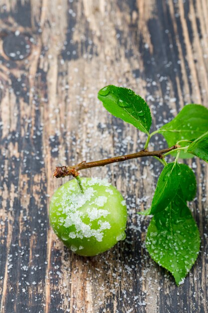 Salzige grüne Pflaume mit hohem Blickwinkel des Zweigs auf eine Holzwand