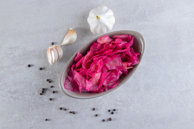 Salziger Kohl in Scheiben mit frischem Knoblauch und Pfefferkörnern.