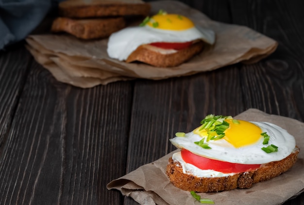 Sandwich auf Toast mit Frischkäse, einer Tomatenscheibe und einem Spiegelei