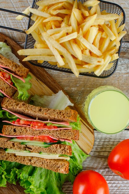 Sandwich mit Limonade, Pommes Frites, Tomaten flach auf Holz und Schneidebrett liegen