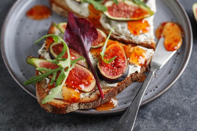 Sandwich-Toast mit Feigen auf Frischkäse mit Marmelade auf Teller serviert