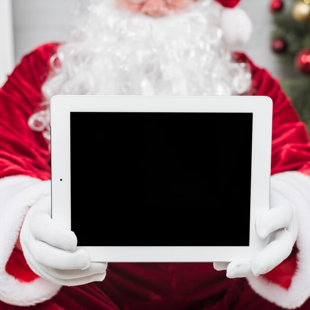 Santa Claus, die Tablette in den Händen hält