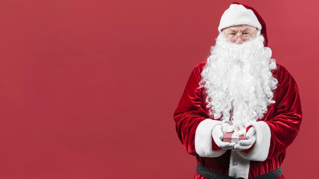 Santa Claus im Hut, der kleine Geschenkbox hält