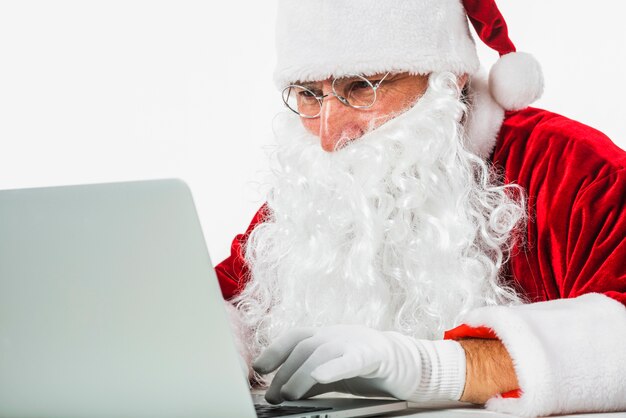 Santa Claus in den Gläsern, die Laptop verwenden